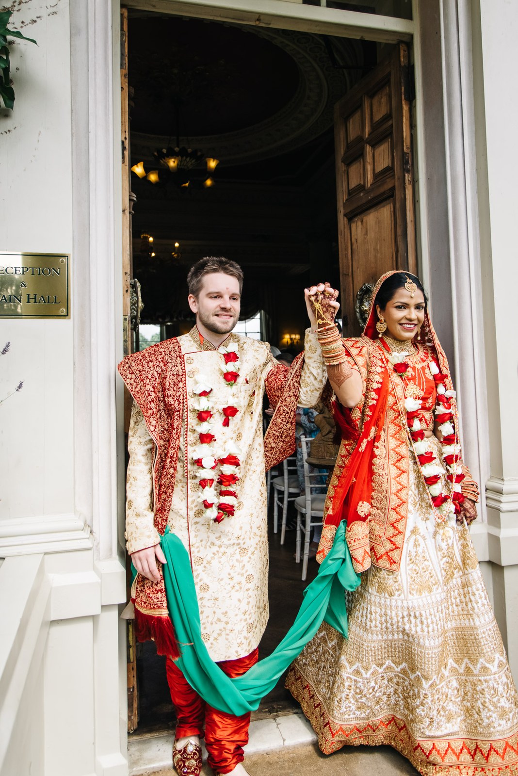 The couple raising joined hands in the panelled doorway to the Main Hall
