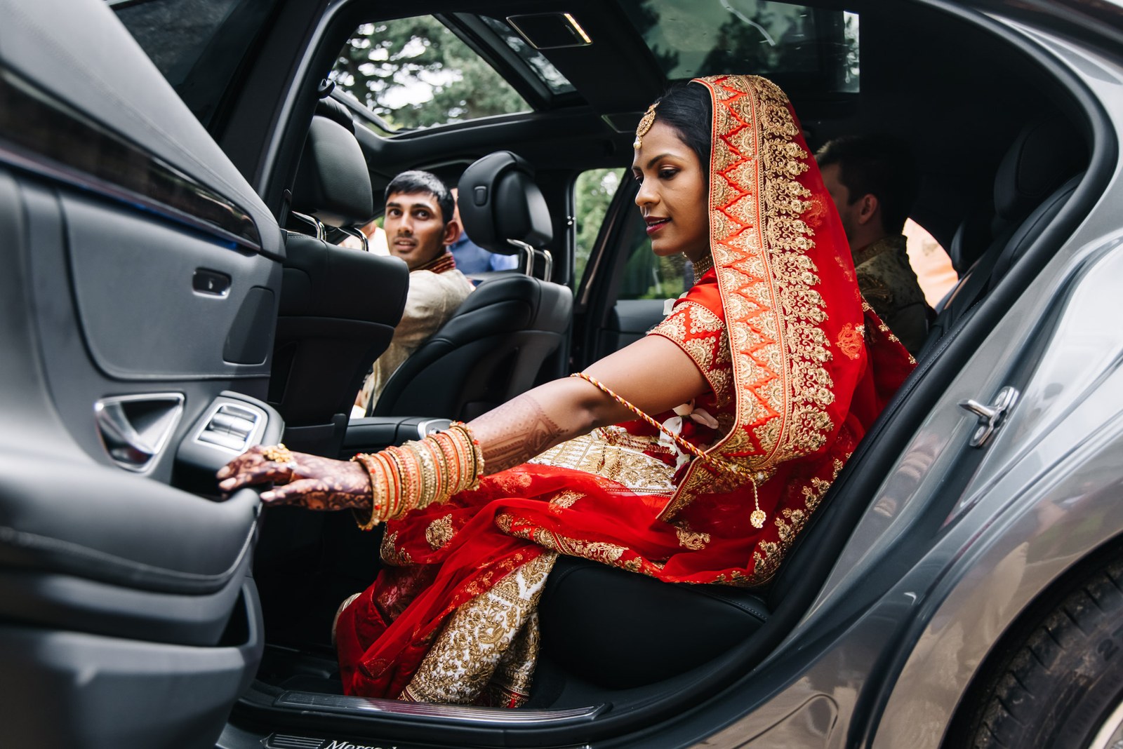 The bride settling into the wedding car, henna hand resting on the door