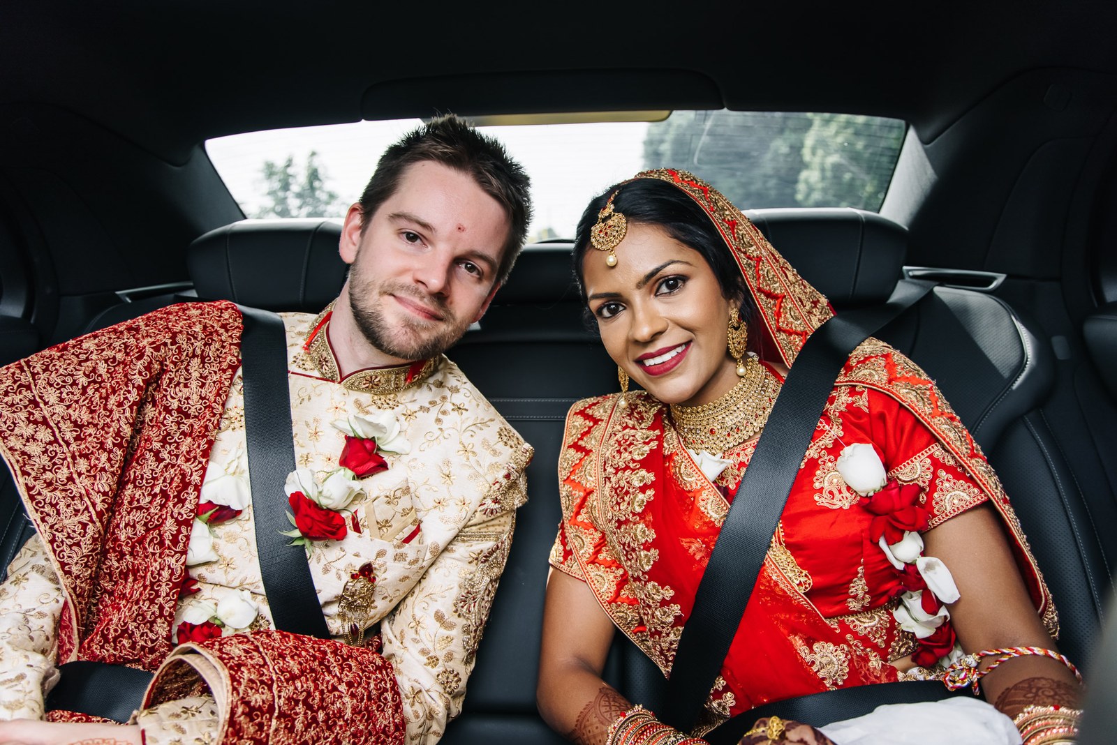 The newlyweds side by side in the back of the car, still in ceremony dress