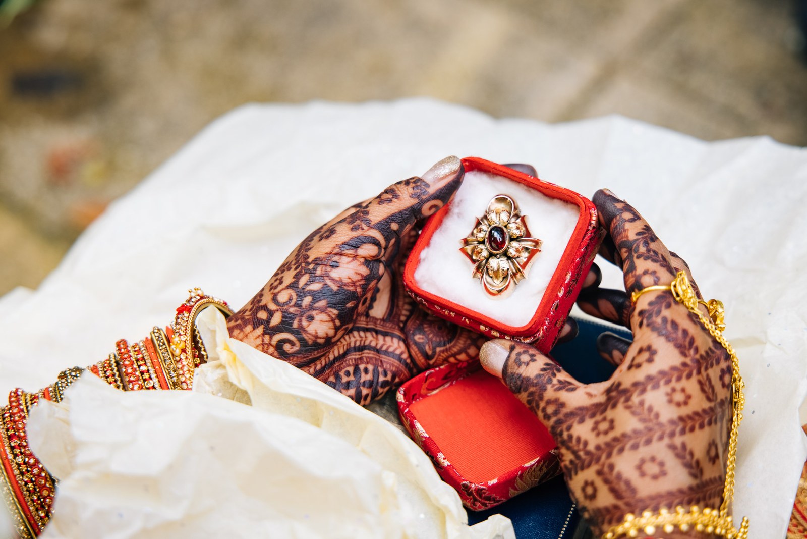 Henna-patterned hands holding open a jewelled ring box