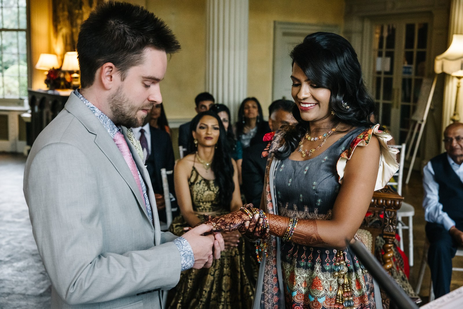 The couple exchanging rings during the ceremony as guests look on