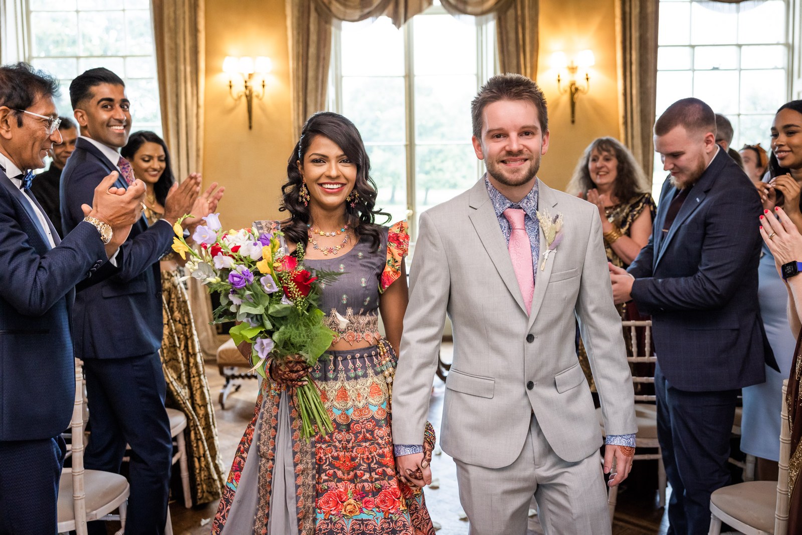 The smiling couple walking back down the aisle as guests clap