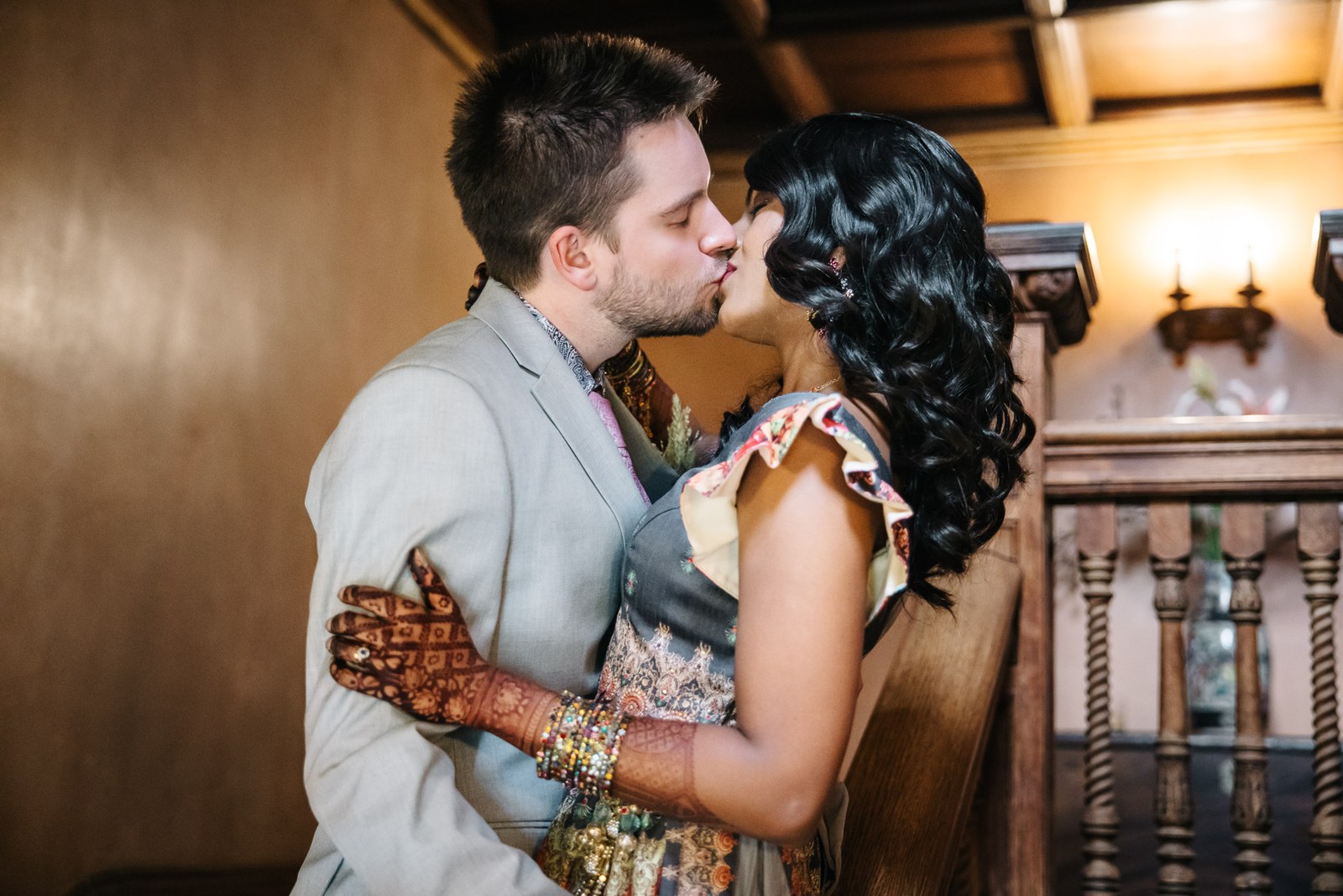 The couple kissing beside the barley-twist wooden staircase at Hampton Court House