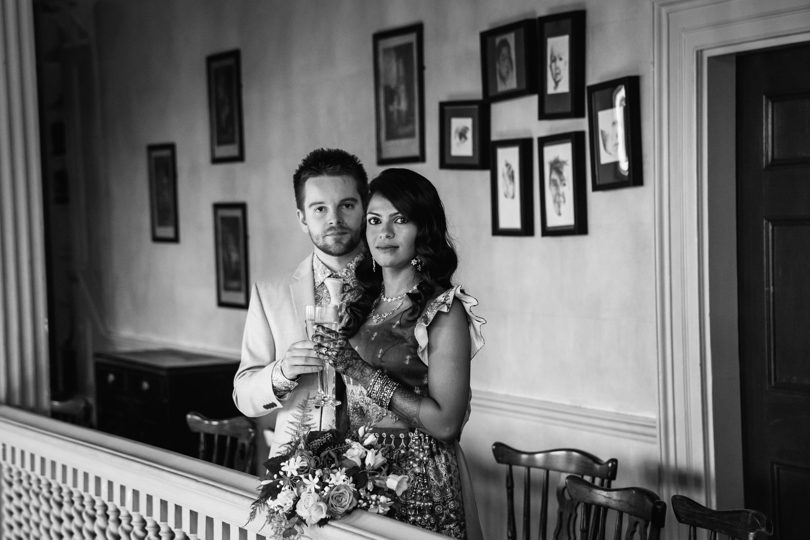 The couple reflected in a mirror below a cluster of framed pictures