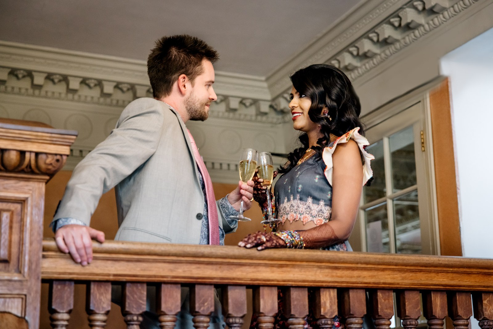 The couple toasting each other at the carved timber balustrade