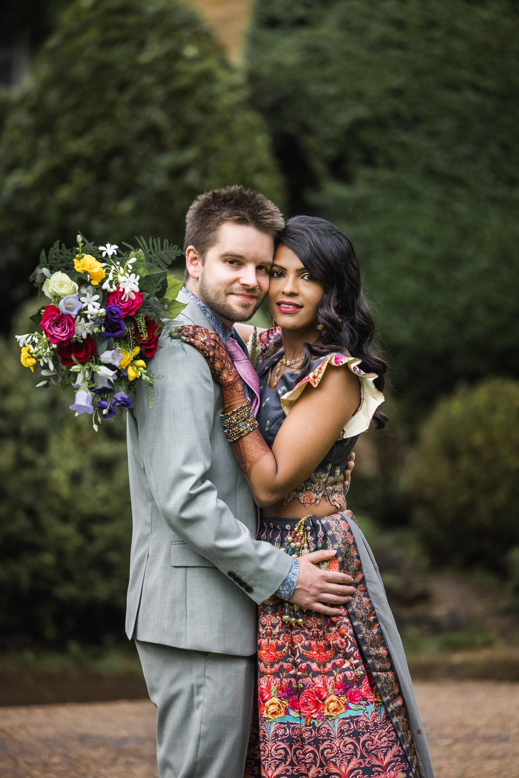 The couple cheek to cheek in the garden, bouquet resting on his shoulder