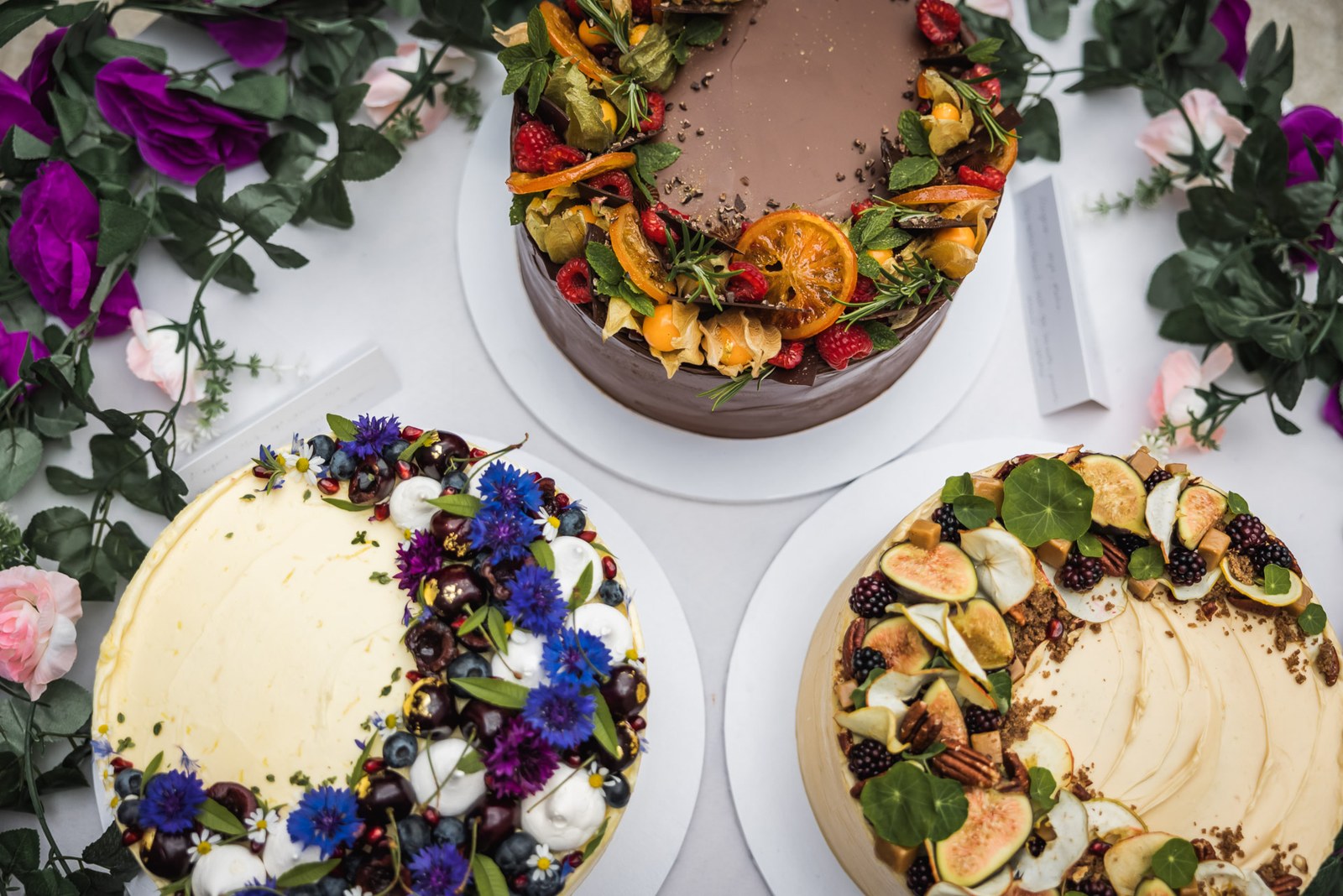 Overhead view of naked celebration cakes dressed with fruit and flowers