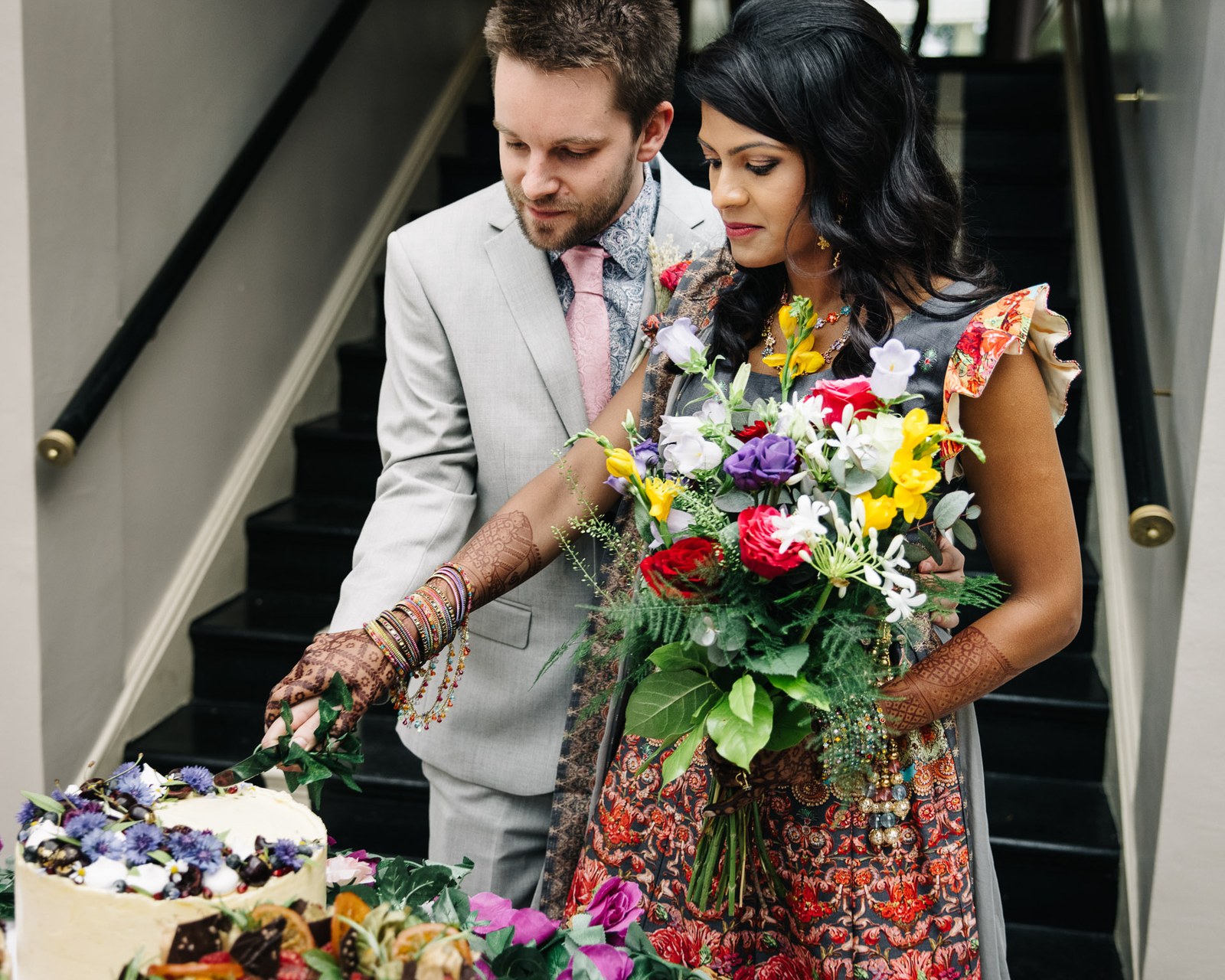 The couple cutting their cake at the foot of the staircase