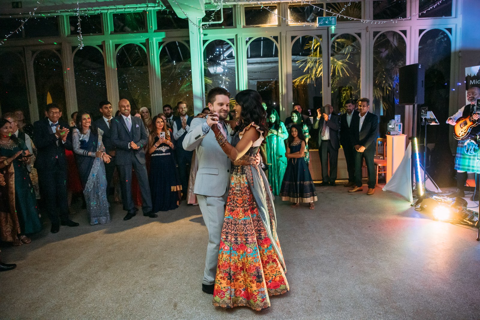 The couple's first dance in the fairy-lit conservatory as guests gather round