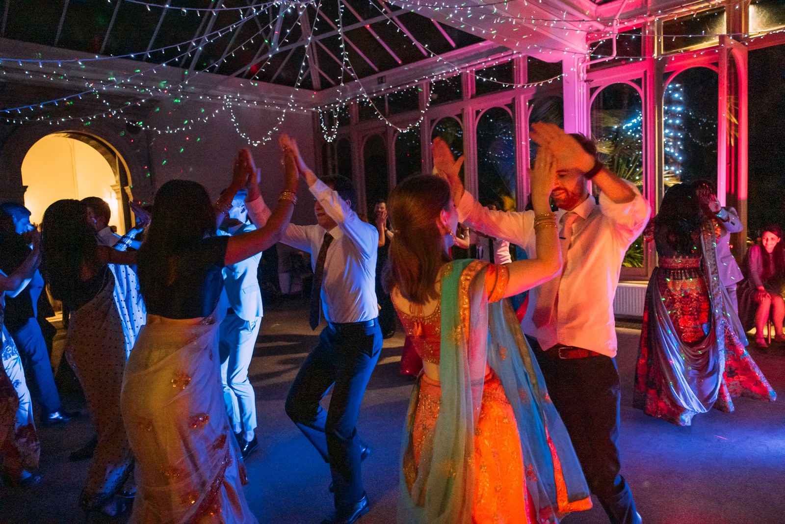 Guests dancing beneath the glazed conservatory roof strung with fairy lights