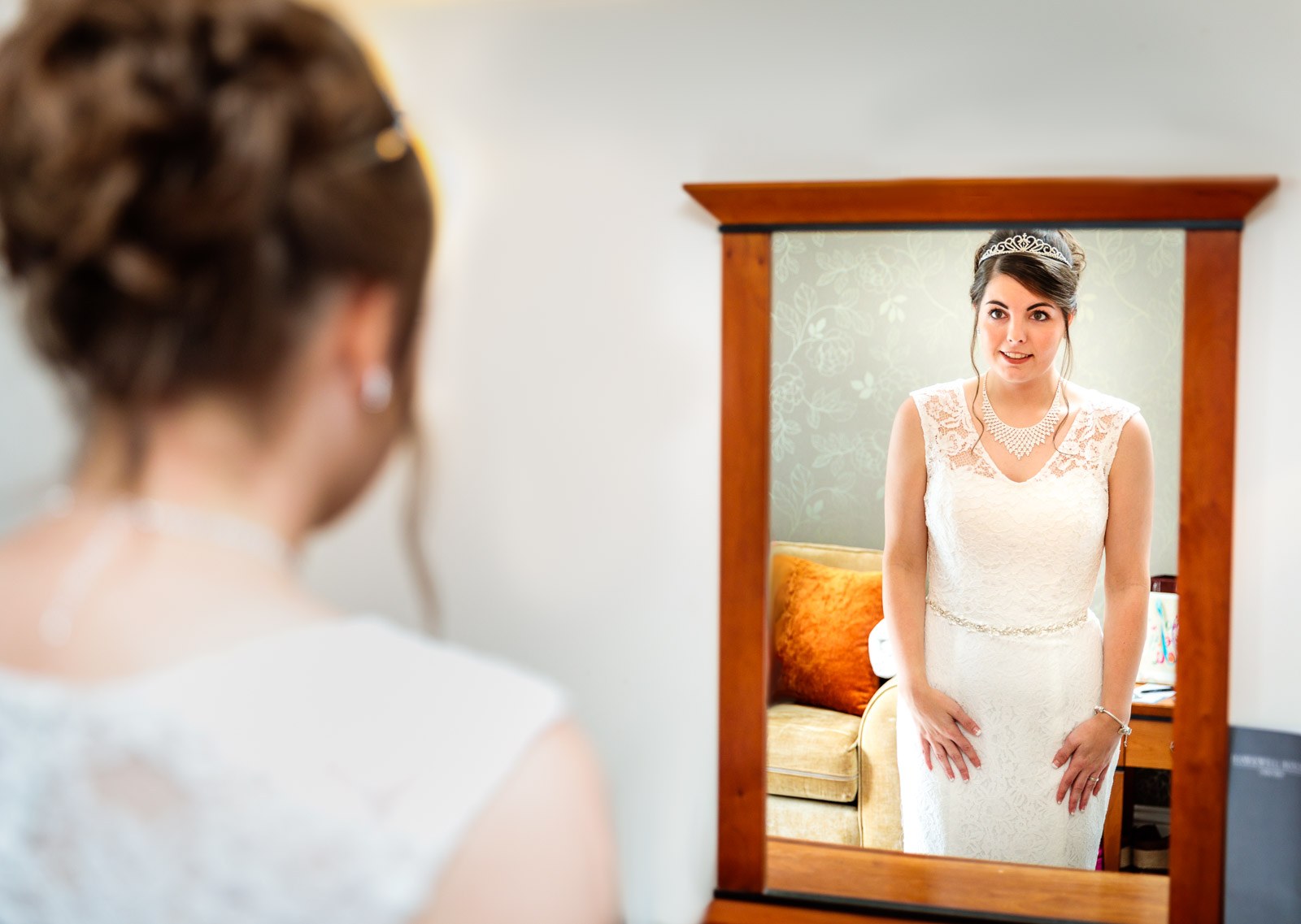 Bride reflected in a mirror as she finishes dressing in the hotel room