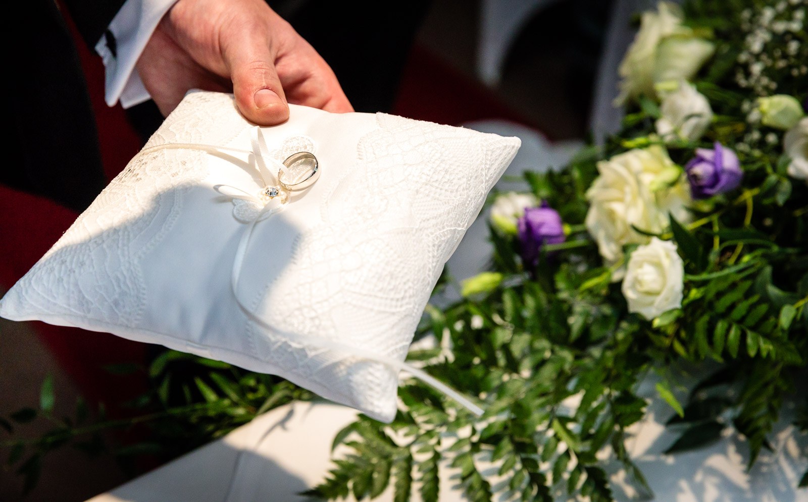 A wedding ring resting on an embroidered ring cushion