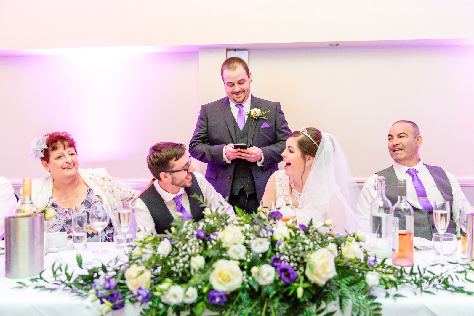 The best man giving his speech as the bride and groom laugh at the top table