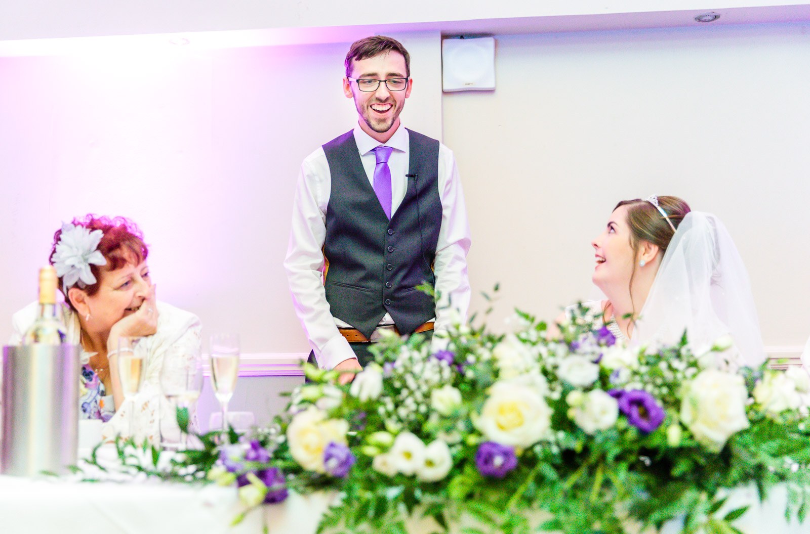 The groom mid-speech at the flower-topped top table