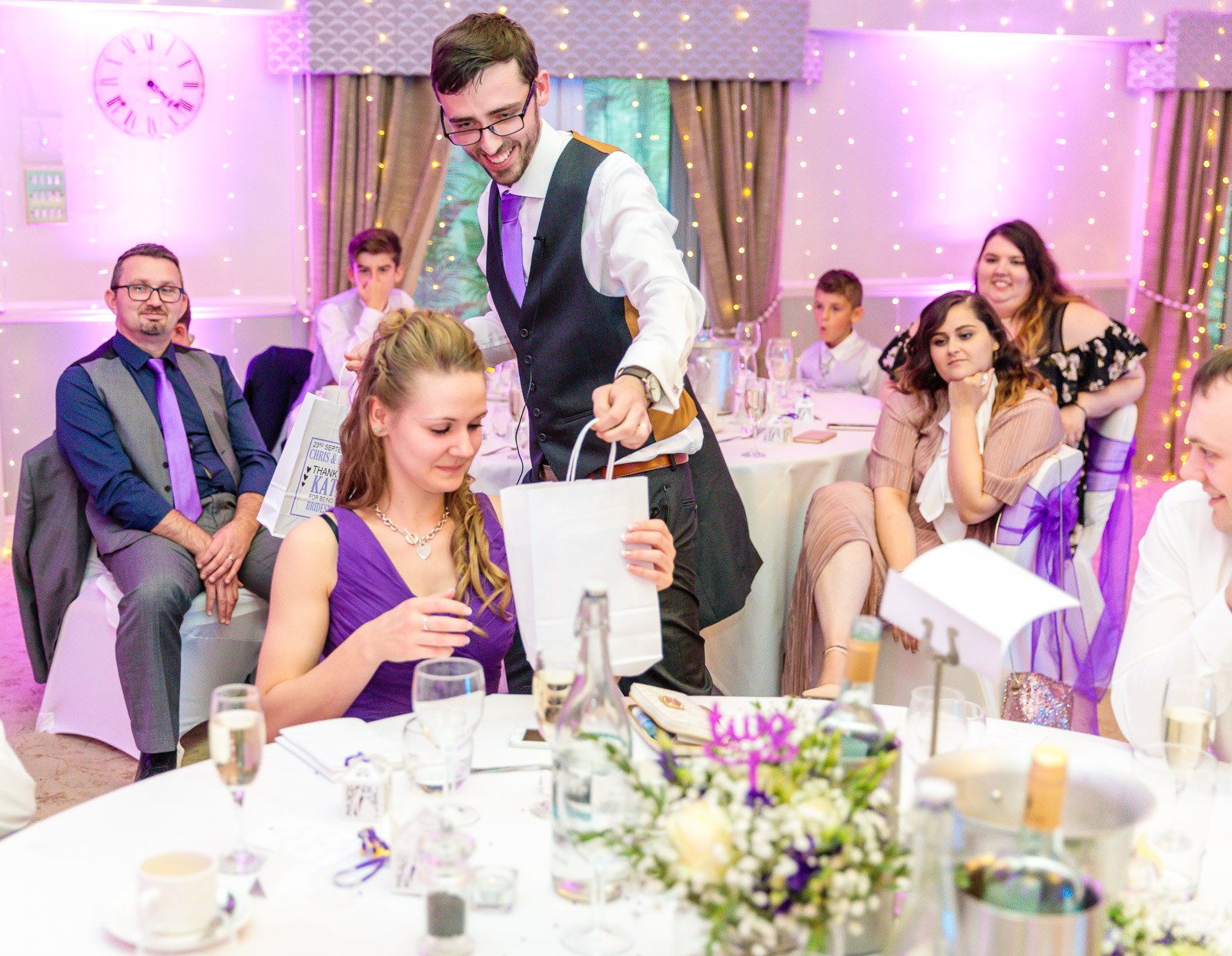 The groom presenting a thank-you gift to a bridesmaid at the table