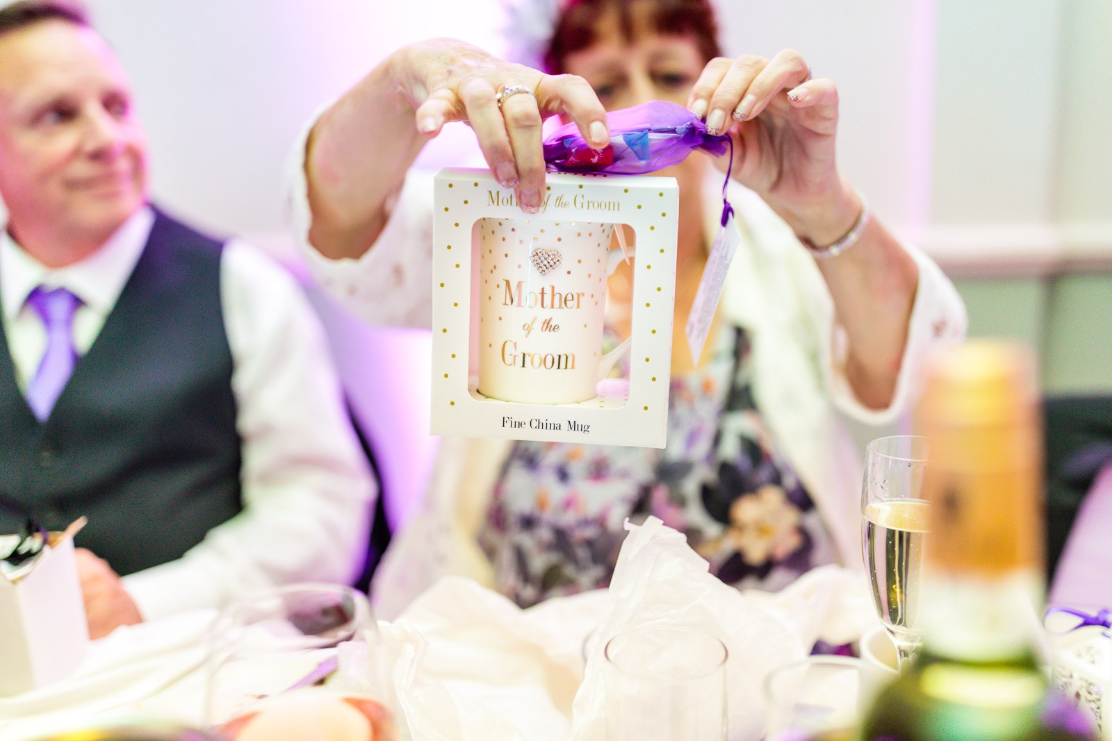 A guest unwrapping a 'Mother of the Groom' keepsake gift