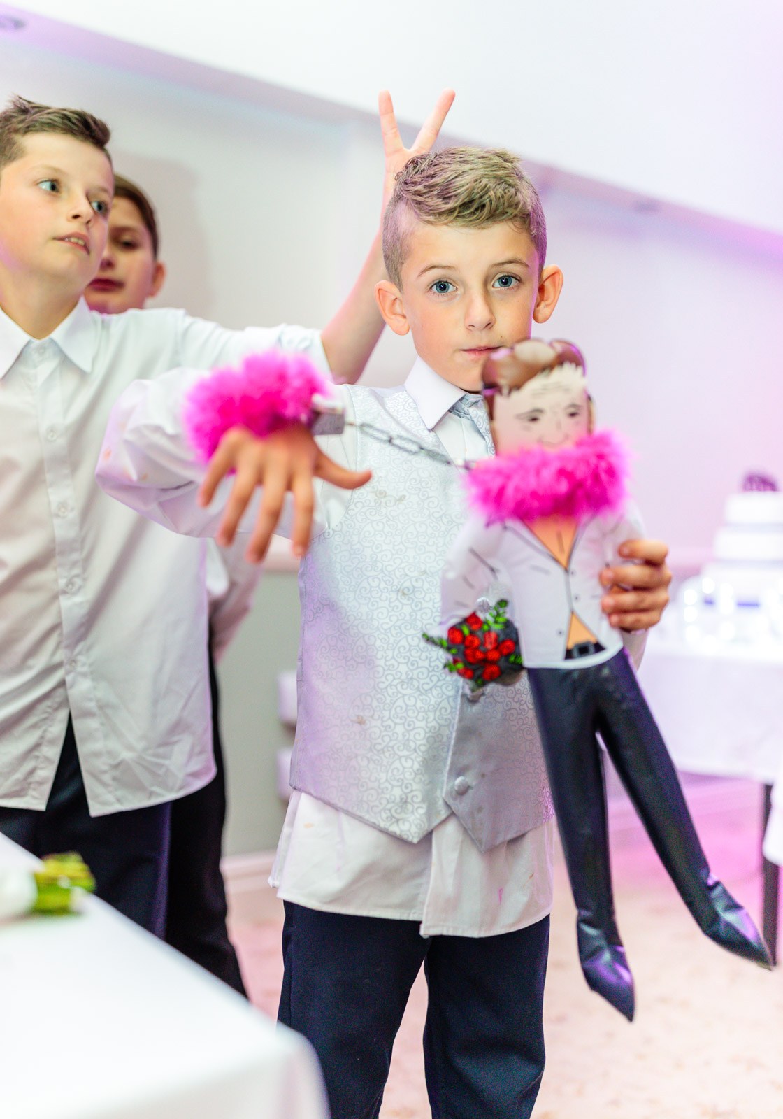 Page boys playing with feathered props near the cake table