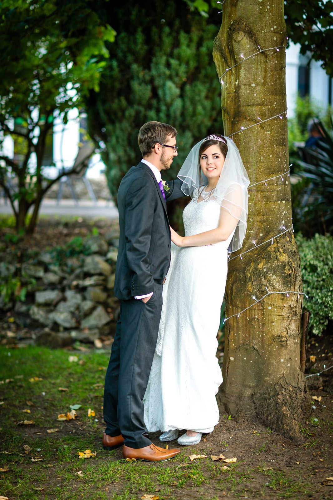 The couple embracing beneath a fairy-lit tree in the hotel garden
