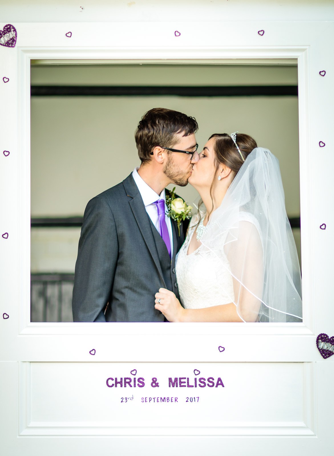The couple kissing inside a personalised photo-booth frame