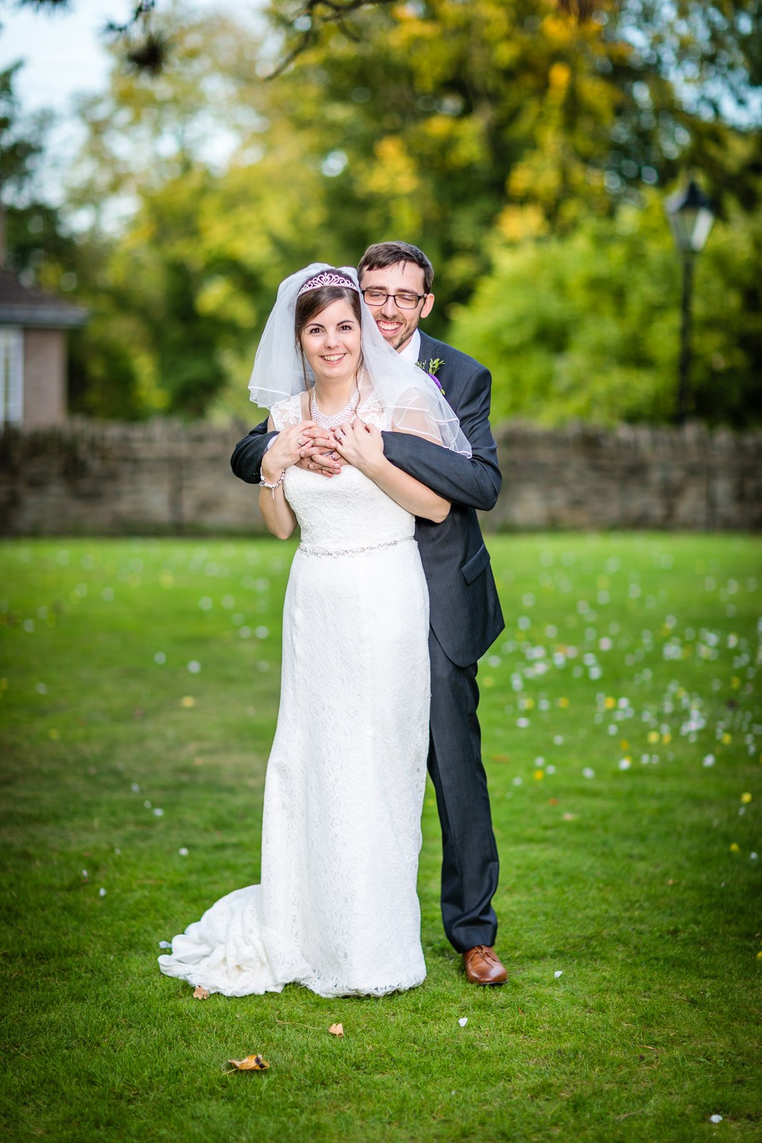 The groom embracing the bride from behind on the lawn