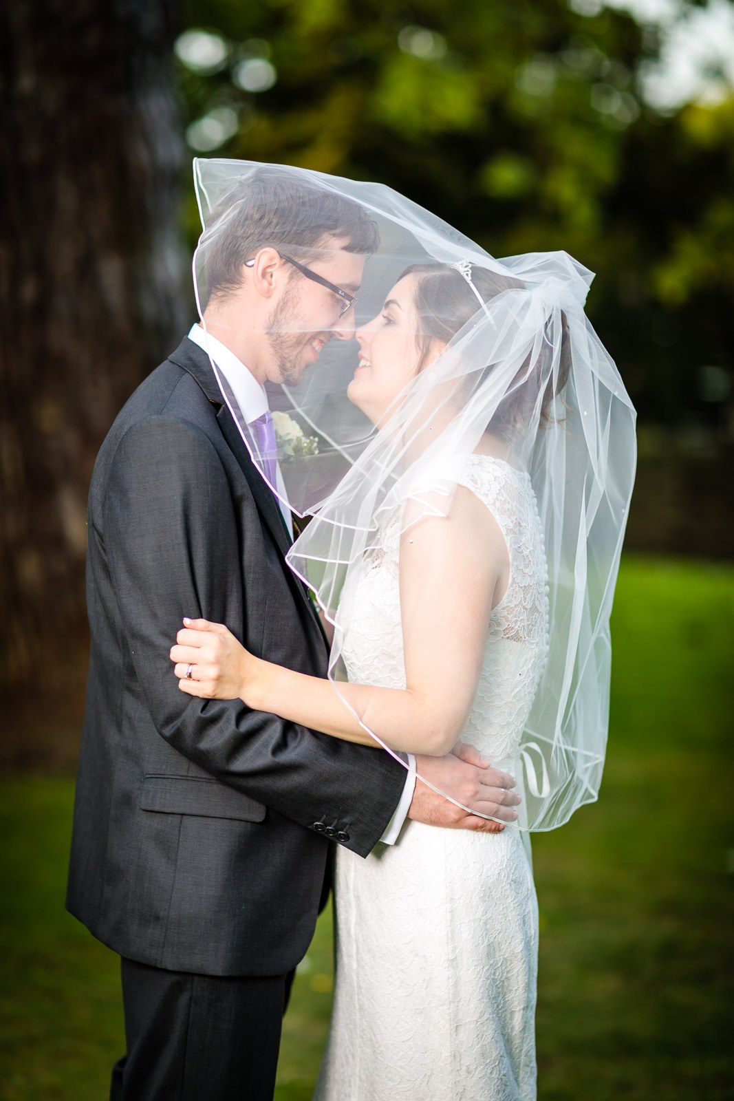 The couple nose to nose beneath the bride's veil