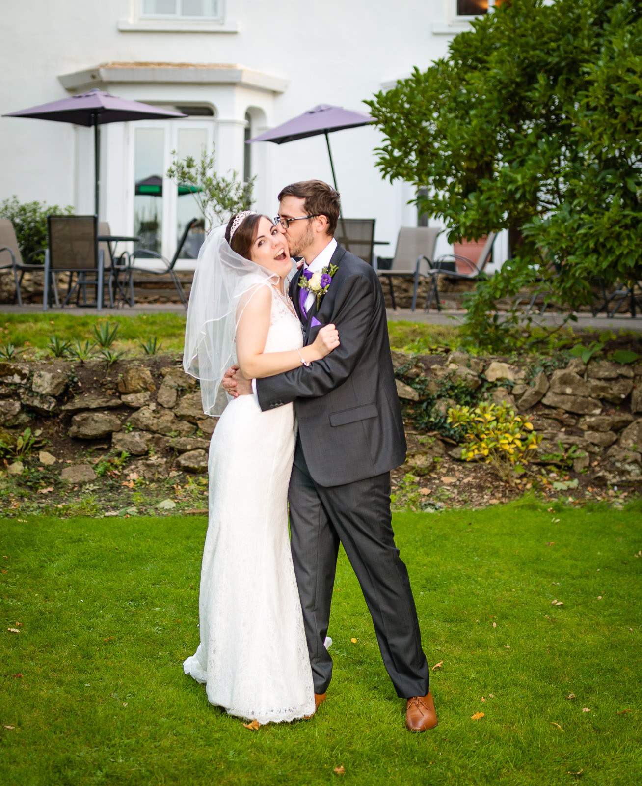 The couple embracing near the umbrella-topped garden terrace