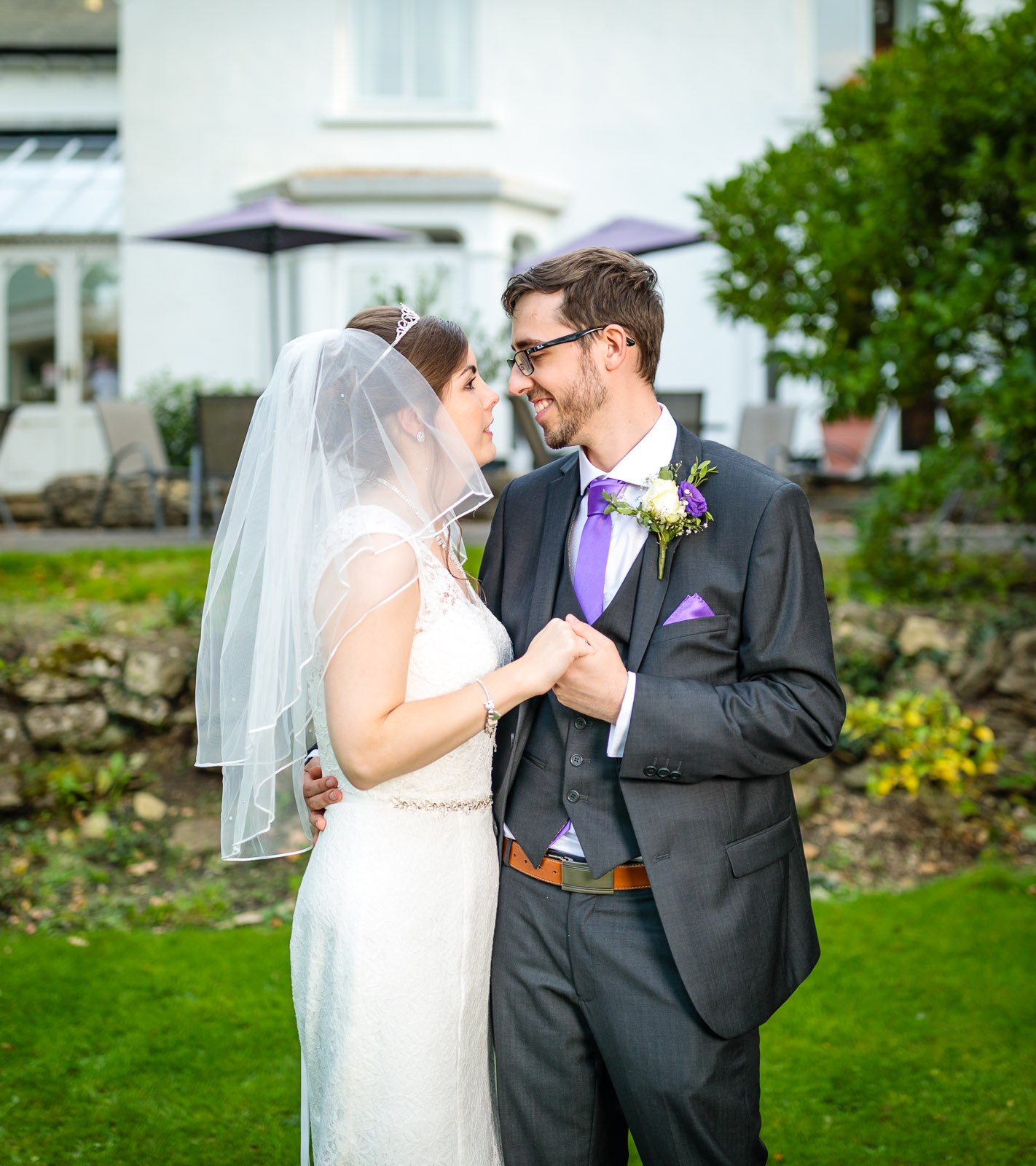 Bride and groom on the lawn before the hotel's patio and parasols
