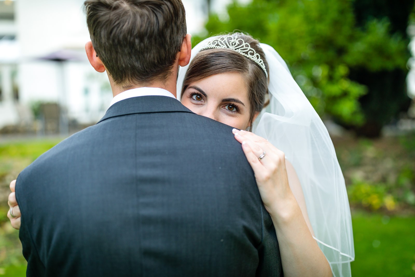 The bride peeking over the groom's shoulder in a warm embrace
