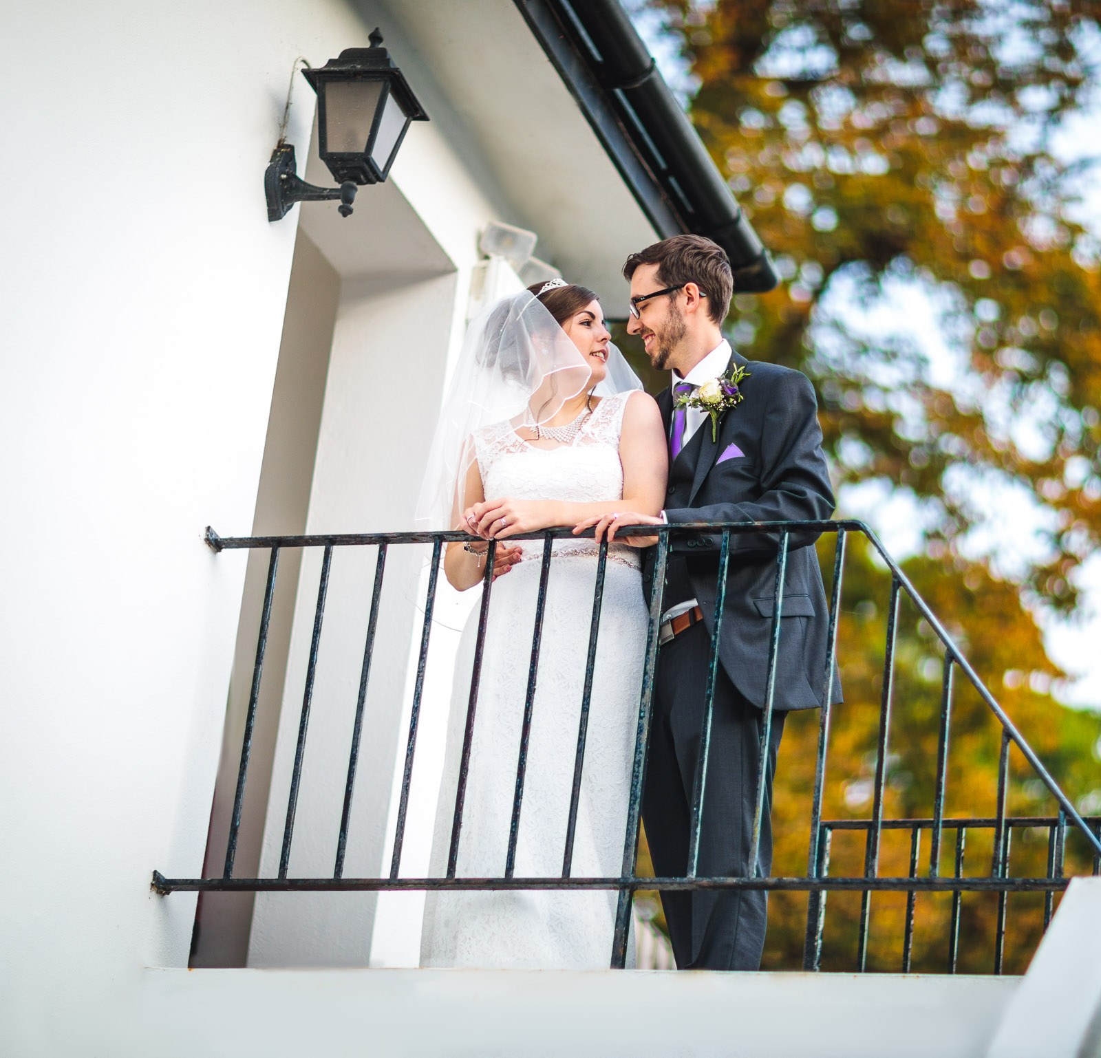 The couple leaning on the terrace railing among autumn foliage at Hawkwell House Hotel