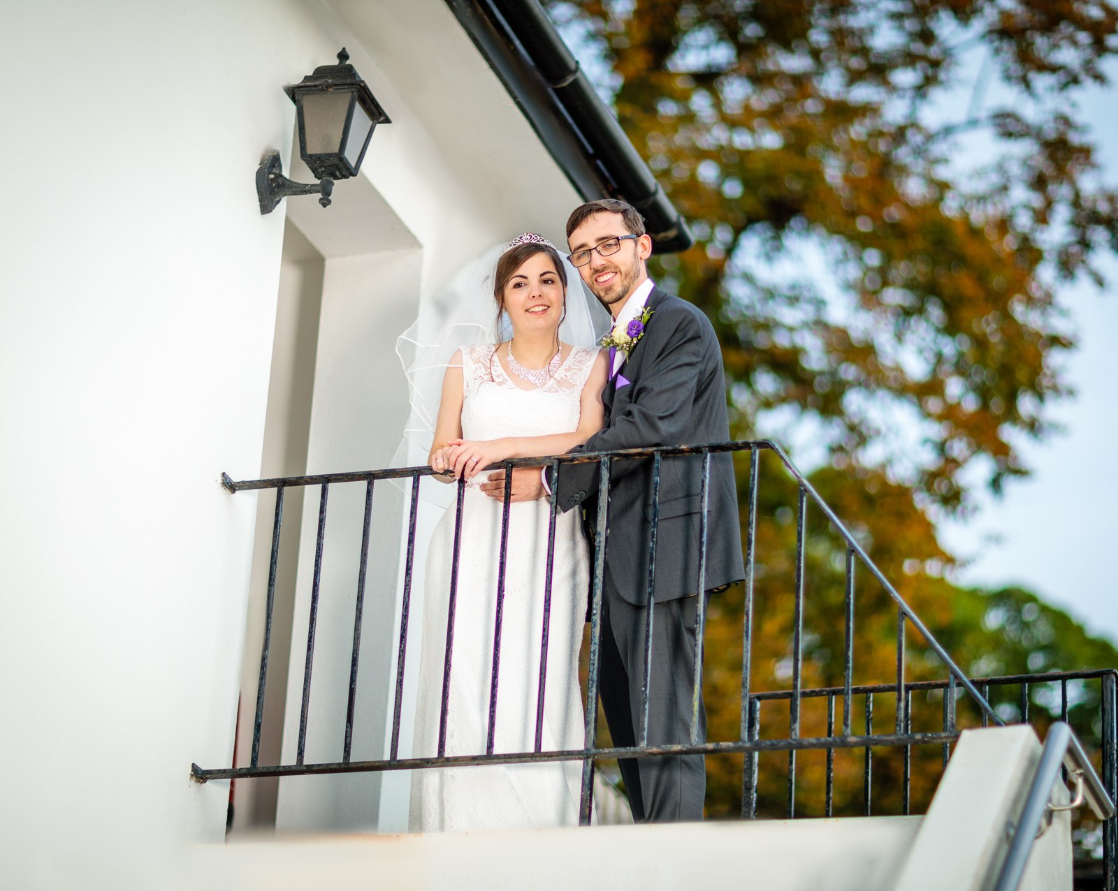 Bride and groom side by side at the balustraded terrace railing