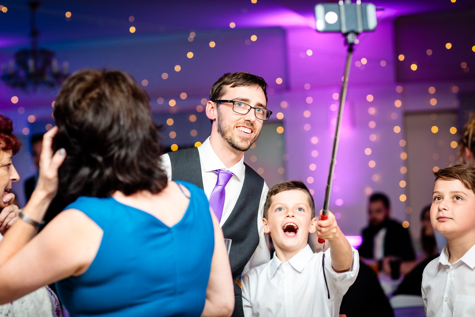 A young guest raising a selfie stick on the dance floor