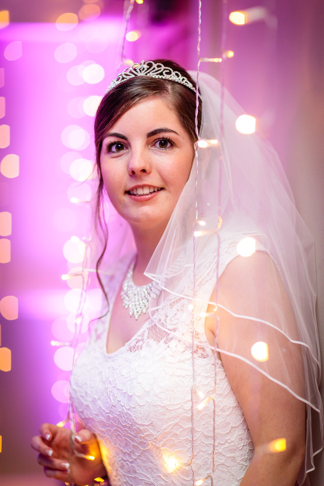 Portrait of the bride against a curtain of warm fairy lights