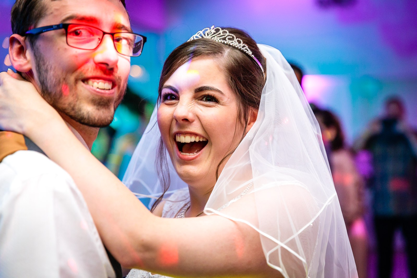 The couple dancing close amid colourful party lighting