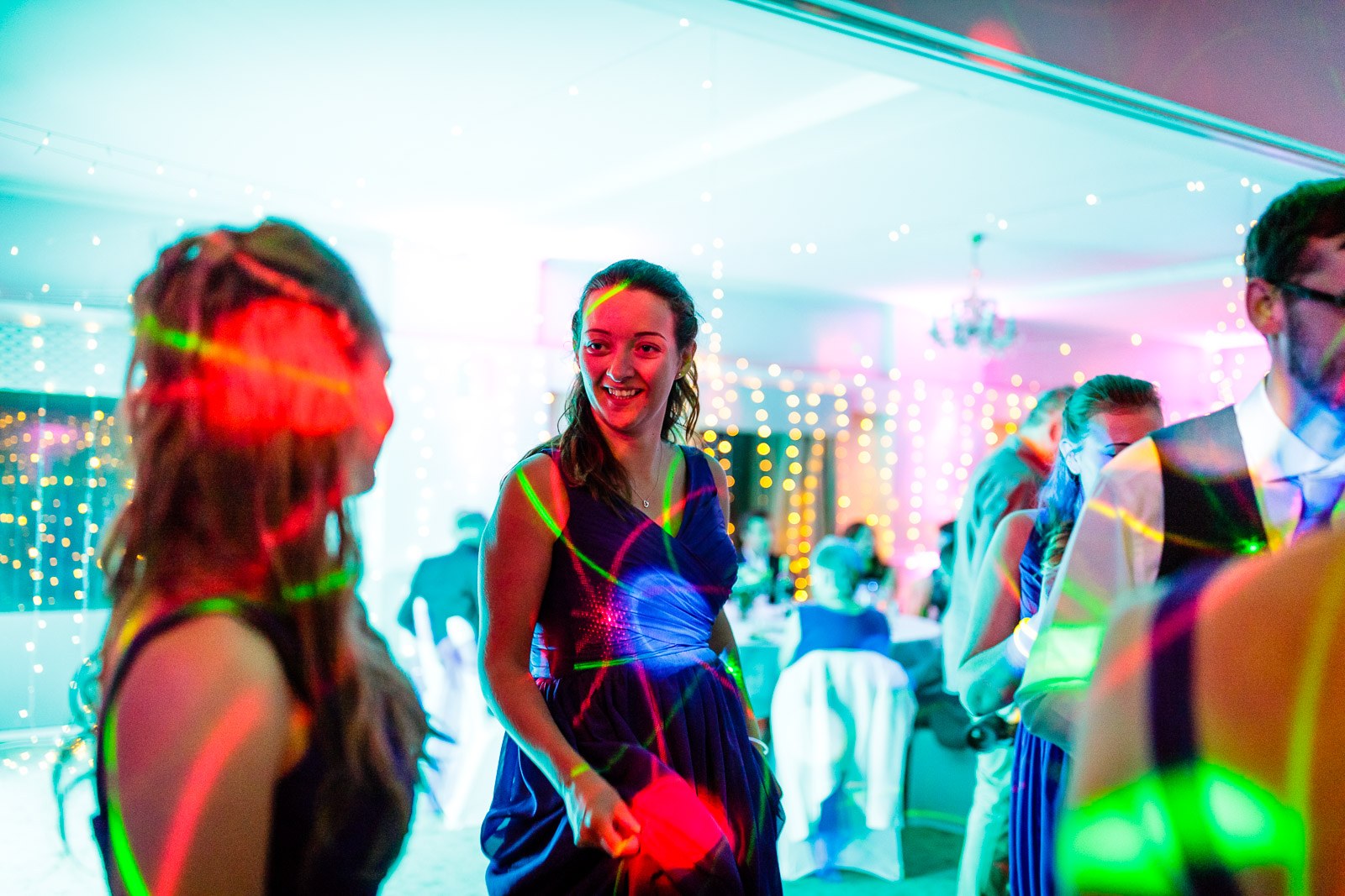 A bridesmaid dancing amid a swirl of coloured party lights