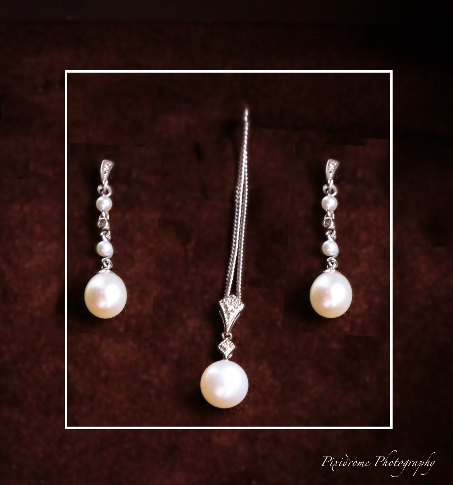 A pearl drop pendant and matching earrings arranged on deep red velvet