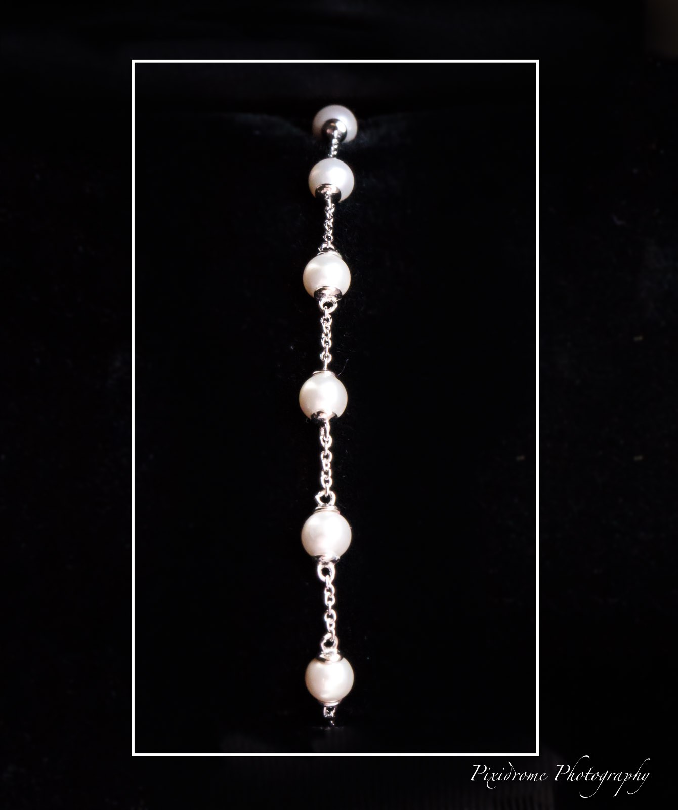A pearl drop necklace displayed against a black background