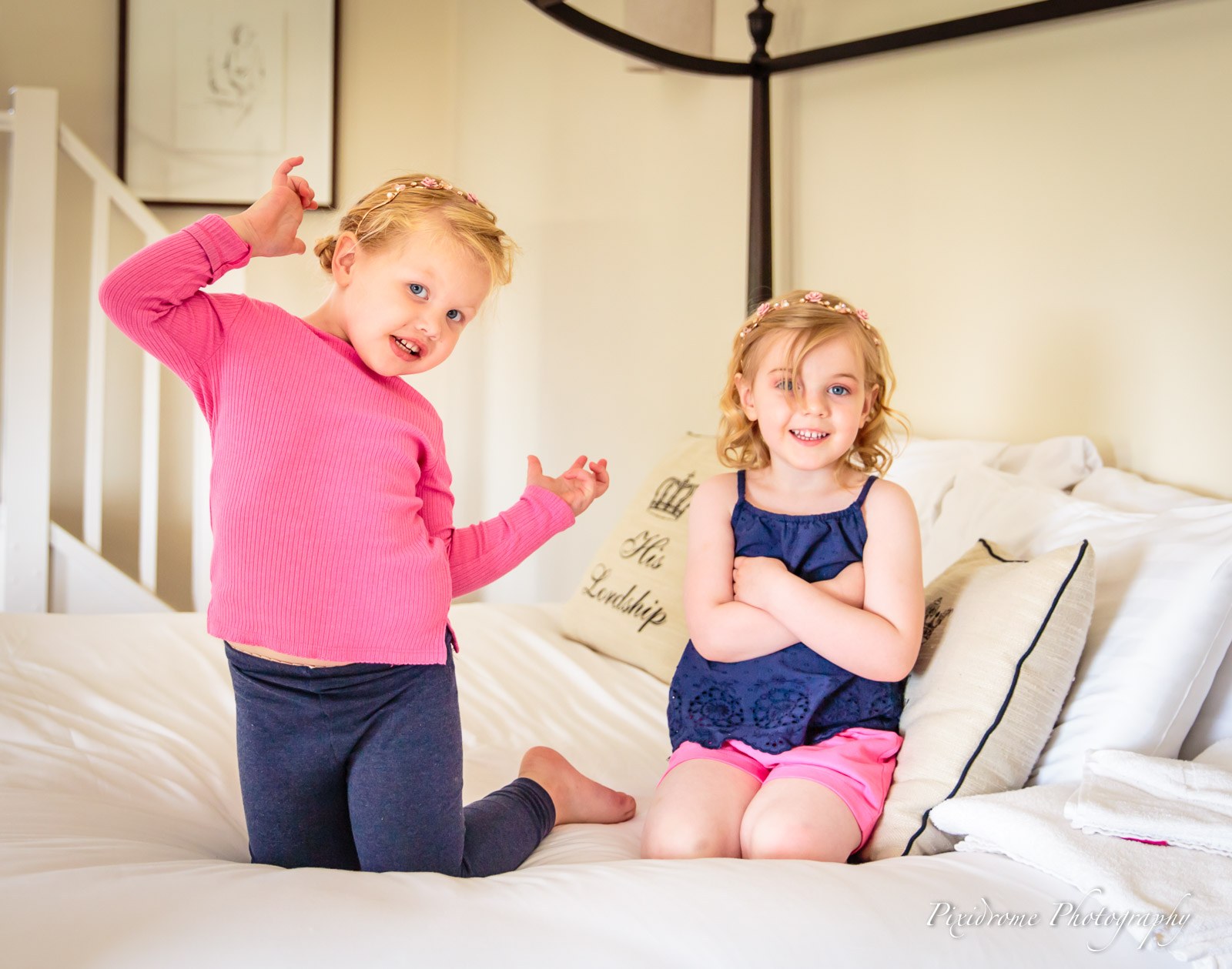 Two little flower girls playing together on the bed during the morning