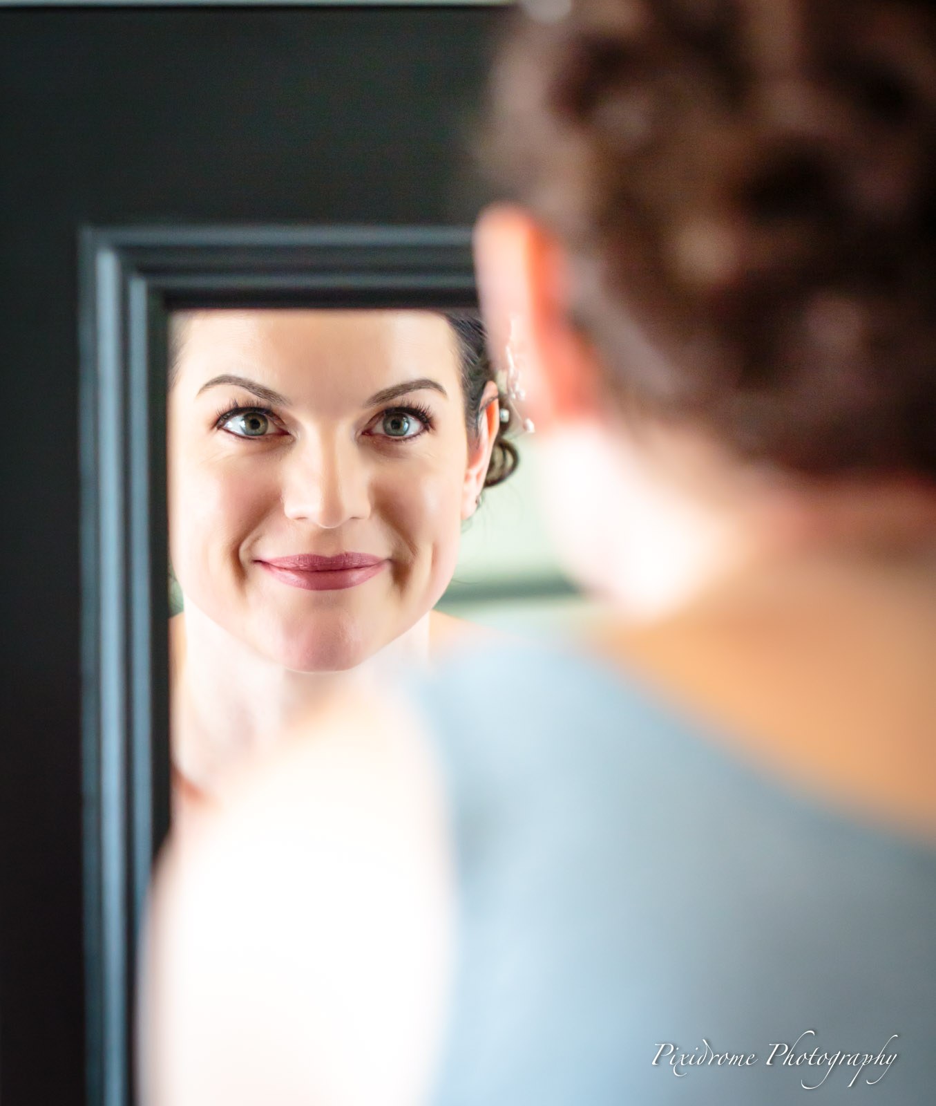 The bride reflected in a framed mirror as she gets ready