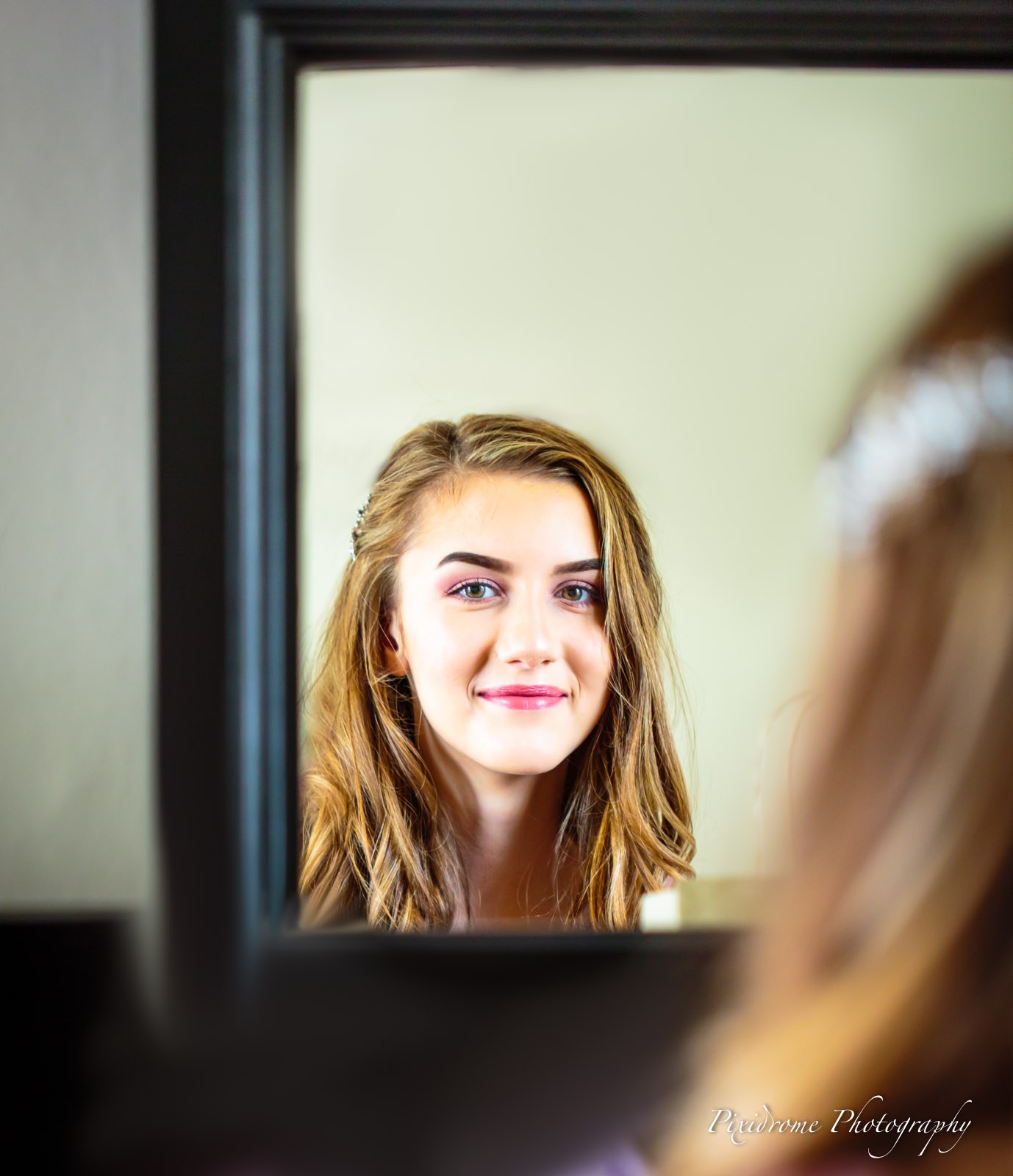 A young bridesmaid in a tiara reflected in a mirror