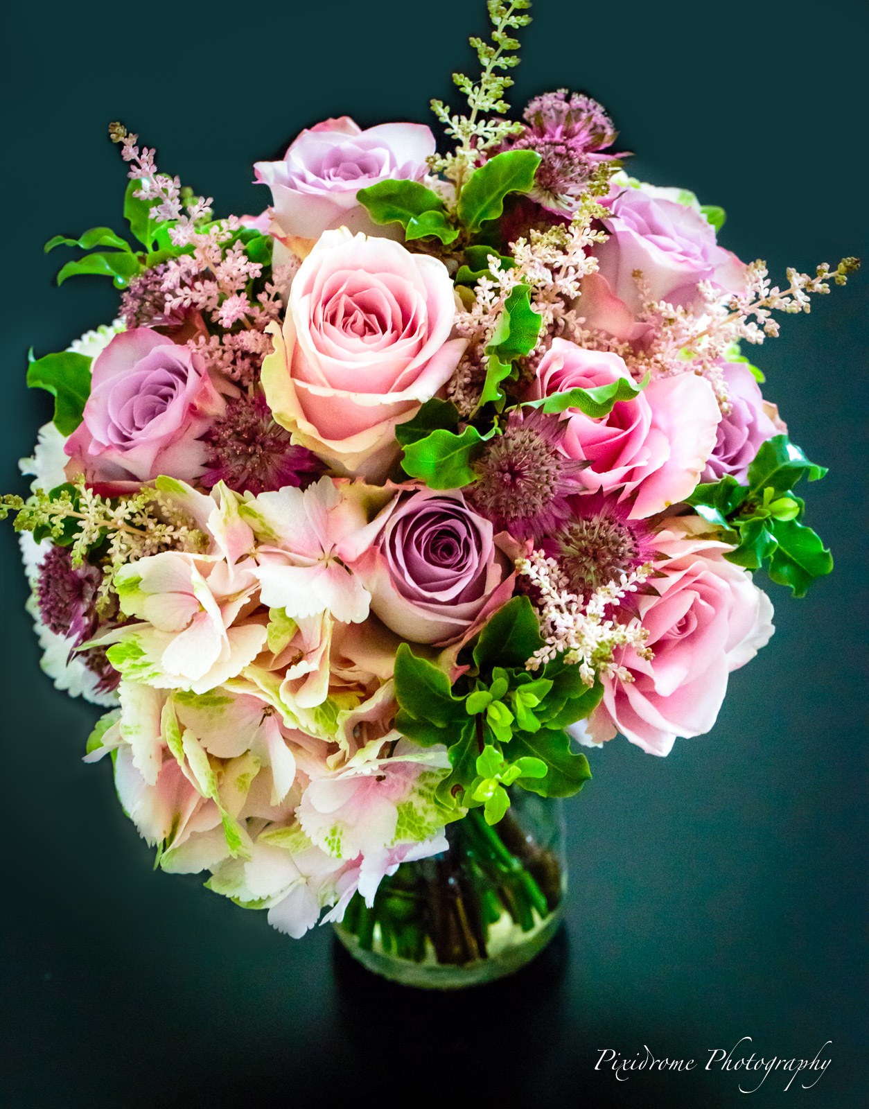A bouquet of pink roses, hydrangea and astilbe in a glass vase