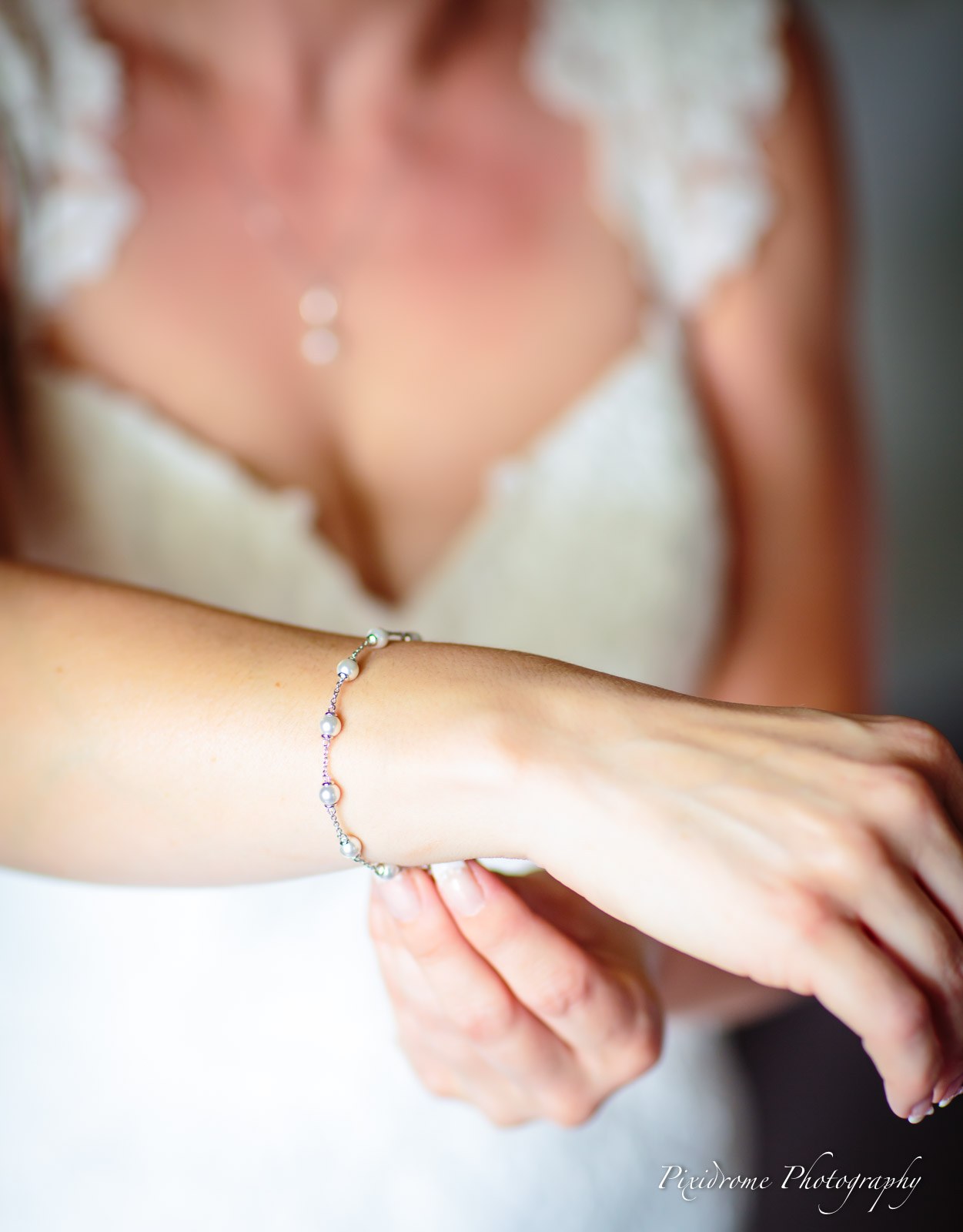 Close-up of the bride's lace neckline and pearl pendant