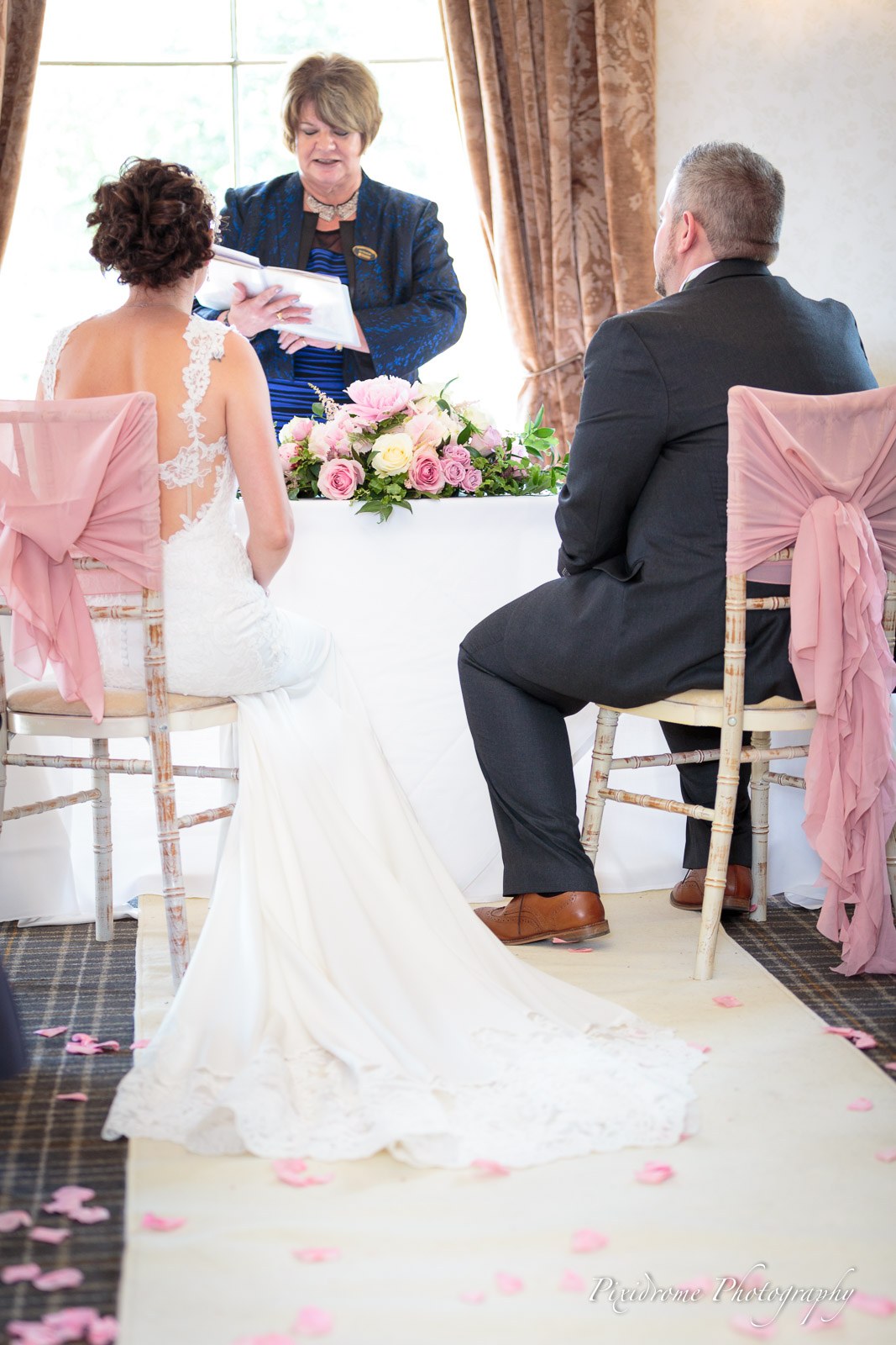 The bride seated at the registrar's table during the ceremony, the groom beside her