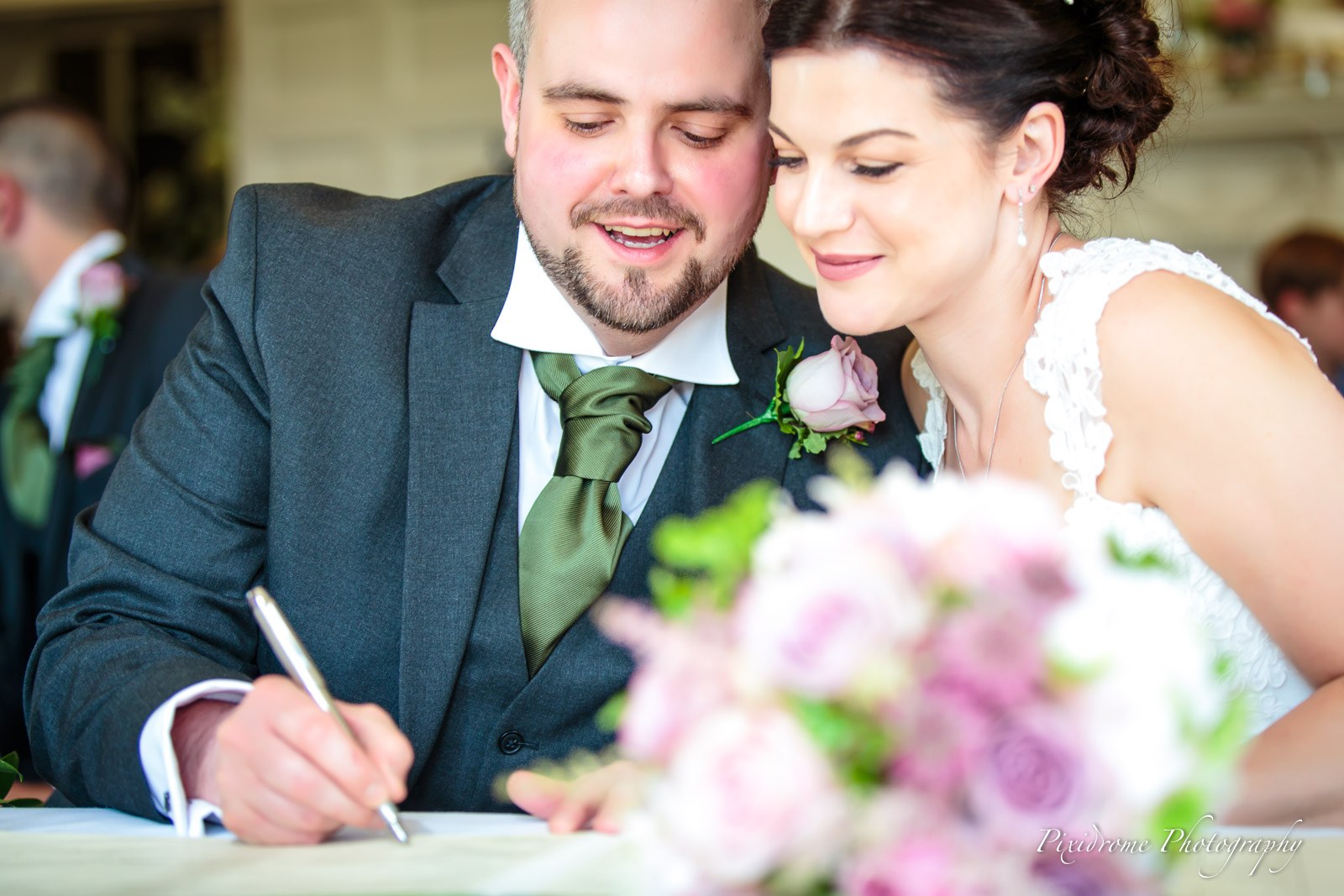 The groom signing the register, the bride's bouquet in the foreground