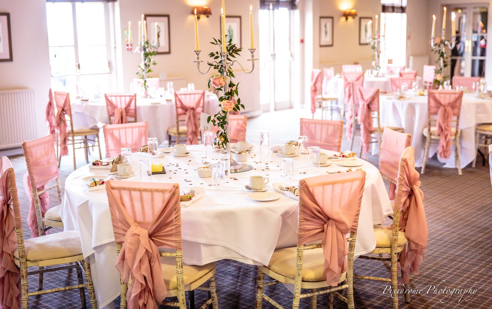 The reception room laid with round tables, pink sashes and gold candelabra at Highfield Park