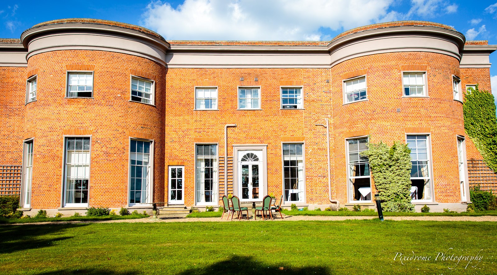 The curved bay of the red-brick facade of Highfield Park above the lawn