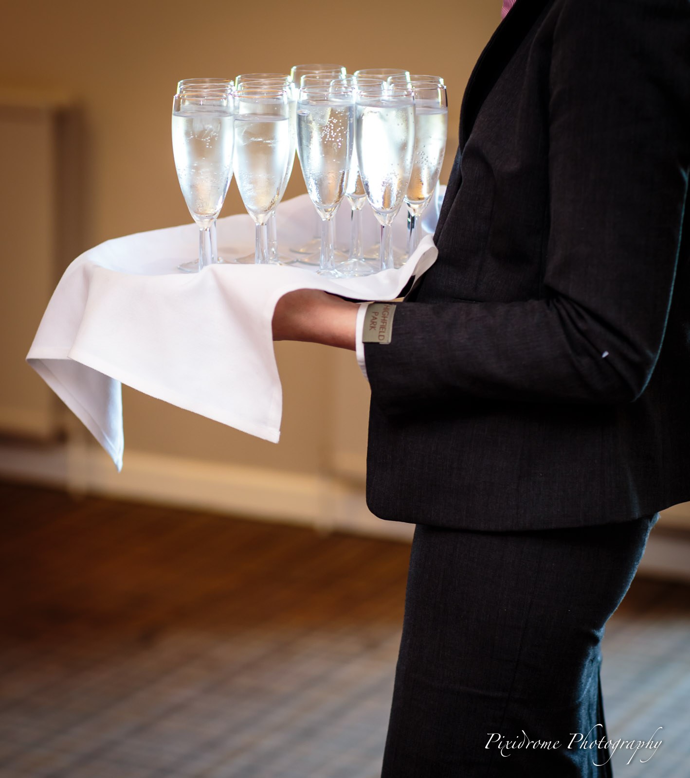A waiter carrying a tray of champagne flutes through the reception