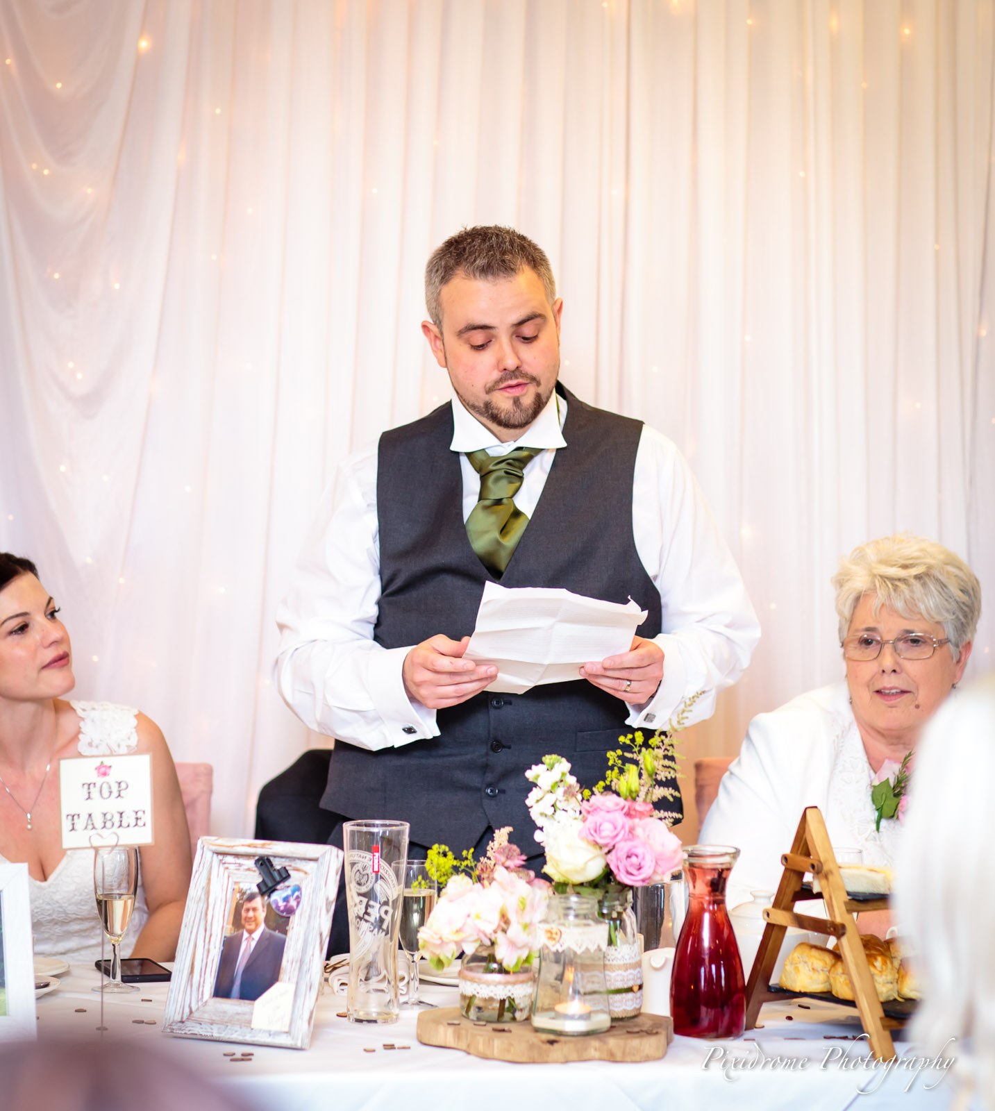 The groom reading his speech at the flower-dressed top table