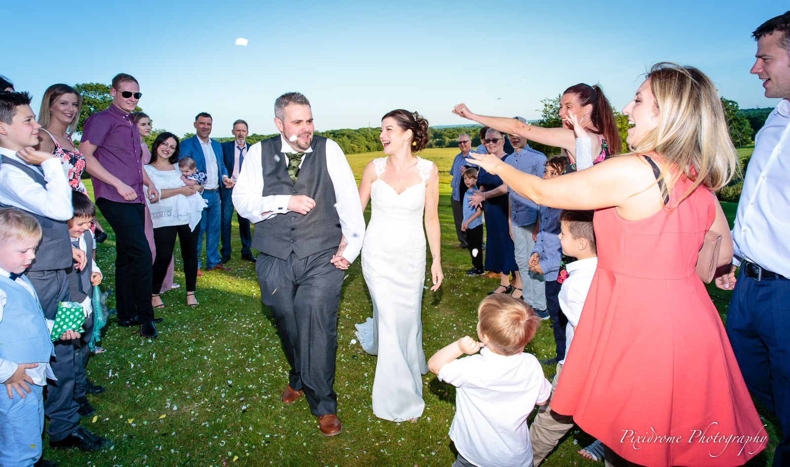 The newlyweds walking out through cheering guests onto the lawn