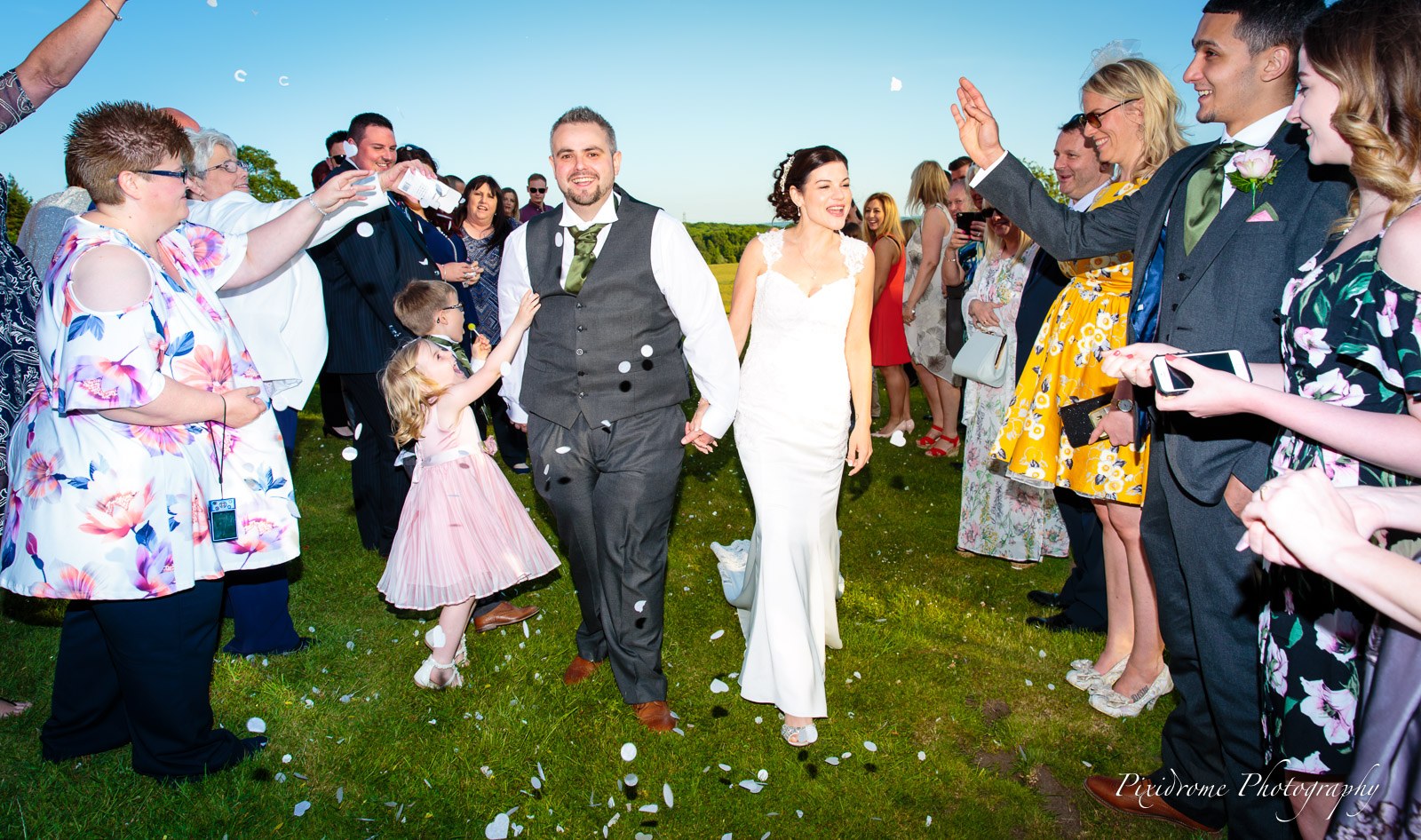 The couple passing through a confetti-throwing tunnel of guests in the grounds