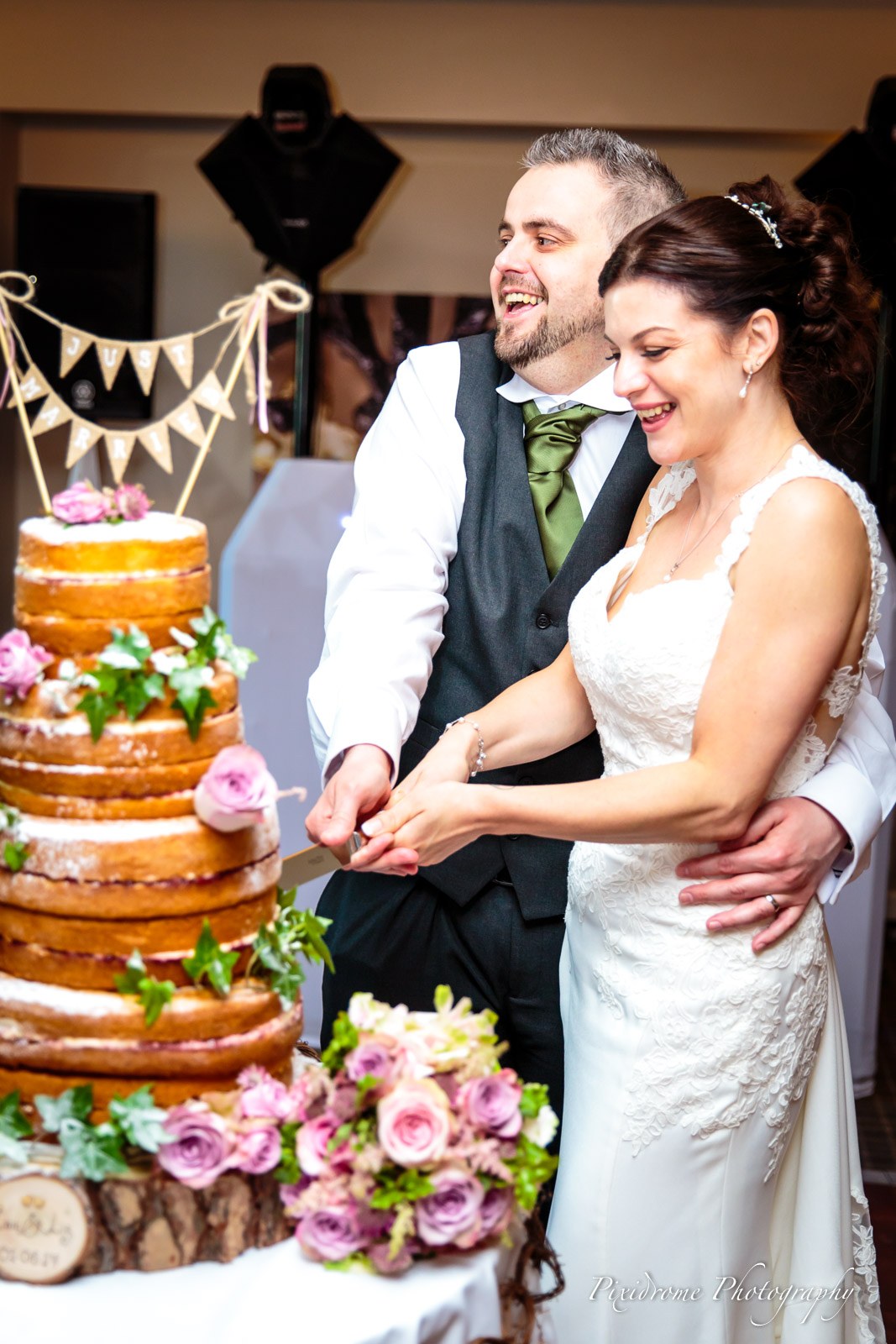 The couple cutting their bunting-topped naked cake together